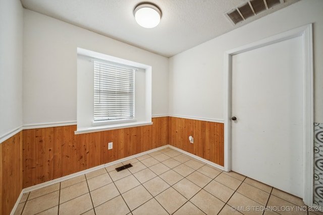 tiled spare room featuring a textured ceiling and wooden walls