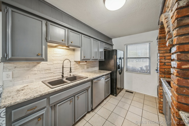 kitchen with gray cabinetry, dishwasher, sink, black refrigerator with ice dispenser, and backsplash