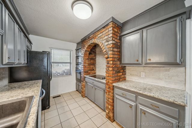 kitchen featuring decorative backsplash, gray cabinets, and black appliances