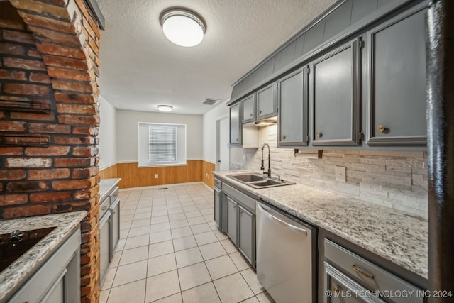 kitchen with tasteful backsplash, light stone counters, dishwasher, and sink