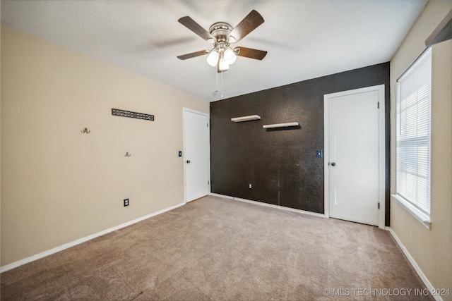 unfurnished room with a wealth of natural light, ceiling fan, and light colored carpet