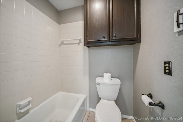 bathroom with tiled shower / bath combo and toilet