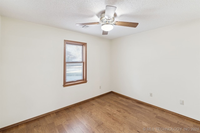 unfurnished room with ceiling fan, light wood-type flooring, and a textured ceiling