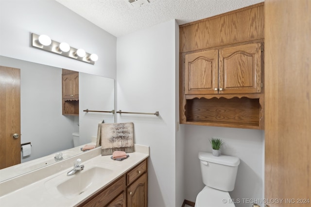 bathroom featuring vanity, a textured ceiling, and toilet