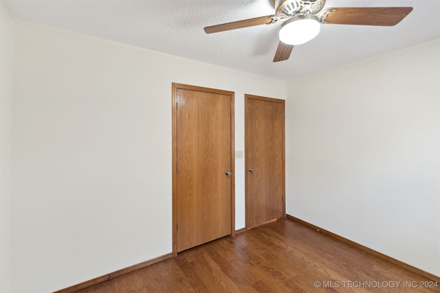 unfurnished bedroom with ceiling fan, wood-type flooring, a textured ceiling, and multiple closets