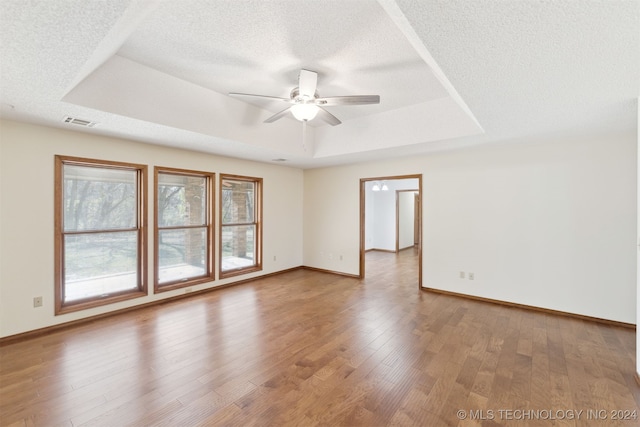 unfurnished room featuring a tray ceiling, ceiling fan, a textured ceiling, and hardwood / wood-style flooring