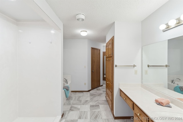 bathroom featuring a textured ceiling, vanity, and a bath