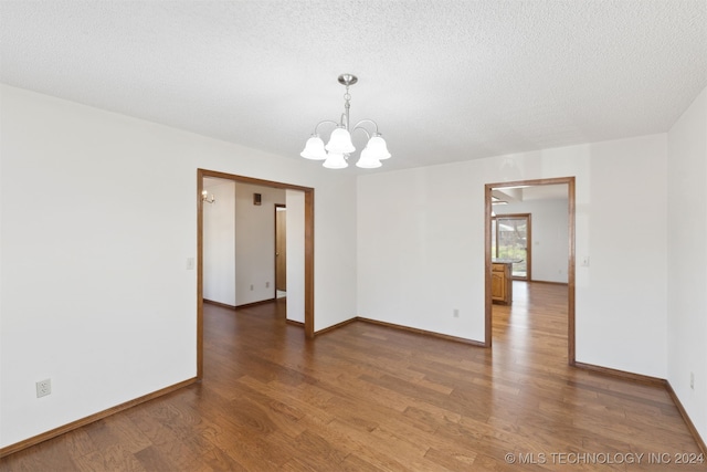 unfurnished room with dark hardwood / wood-style flooring, a textured ceiling, and an inviting chandelier