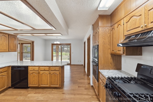 kitchen with black appliances, light hardwood / wood-style floors, light stone counters, kitchen peninsula, and a chandelier