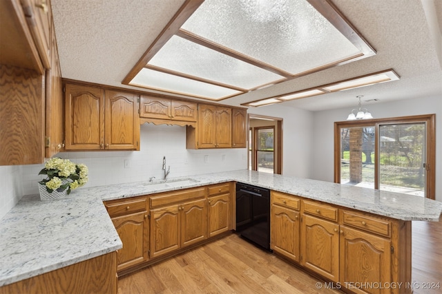 kitchen with kitchen peninsula, sink, black dishwasher, light hardwood / wood-style floors, and hanging light fixtures