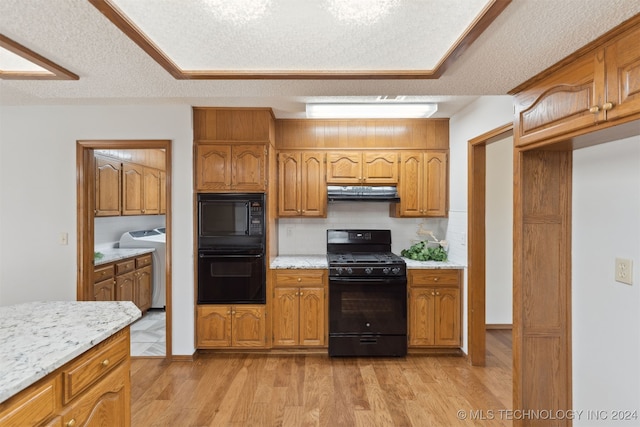 kitchen with backsplash, light hardwood / wood-style flooring, black appliances, and a textured ceiling