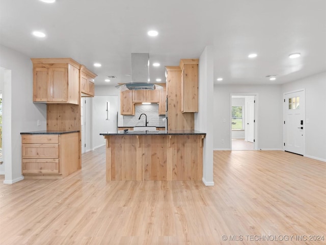 kitchen featuring kitchen peninsula, light brown cabinets, light hardwood / wood-style floors, and island range hood