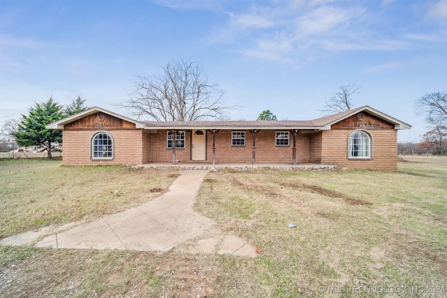 ranch-style house featuring covered porch and a front yard