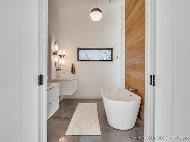 bathroom with a washtub, vanity, concrete floors, and wood walls