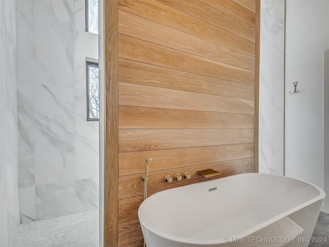 bathroom with a tub to relax in and wooden walls