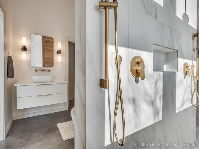 bathroom featuring concrete flooring, vanity, and walk in shower