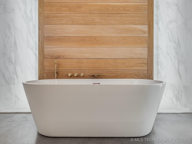 bathroom featuring a washtub, concrete flooring, and wooden walls