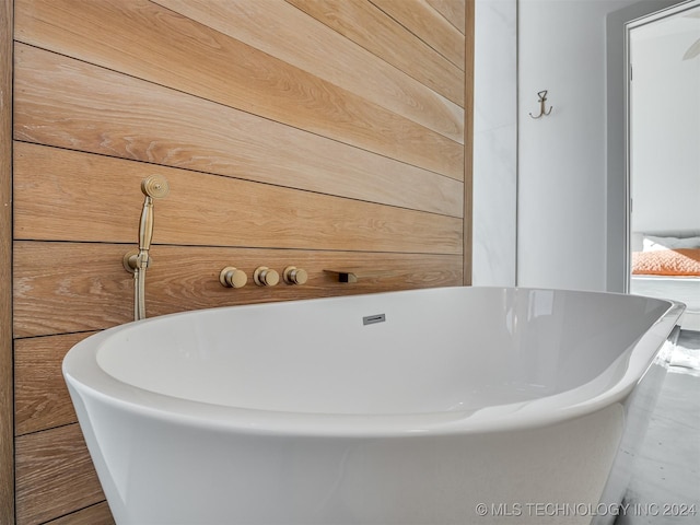 bathroom featuring a tub and wooden walls