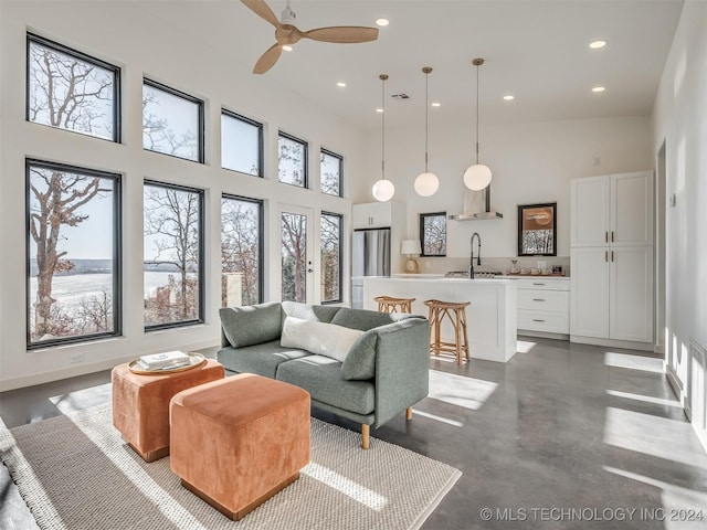 living room with a towering ceiling, ceiling fan, and sink