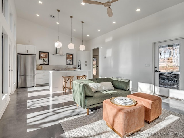 living room with ceiling fan, sink, and a towering ceiling