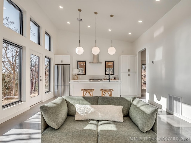 living room featuring sink, high vaulted ceiling, and concrete floors