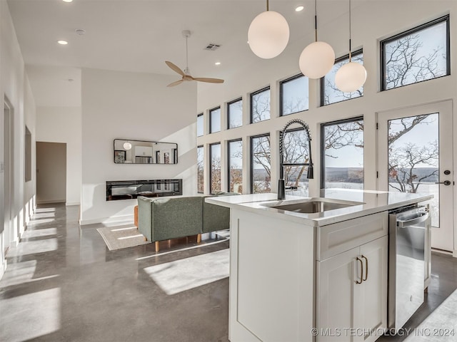 kitchen with pendant lighting, a center island with sink, white cabinetry, and a high ceiling