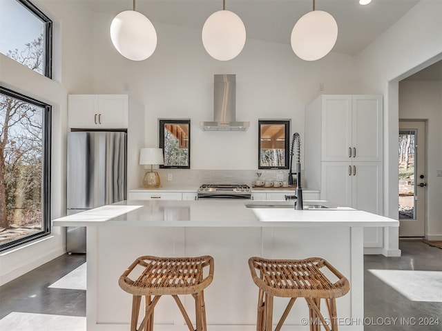 kitchen with white cabinets, appliances with stainless steel finishes, hanging light fixtures, and exhaust hood