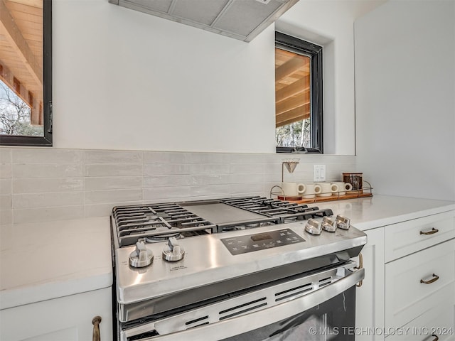 kitchen featuring a healthy amount of sunlight, white cabinetry, extractor fan, and stainless steel gas range