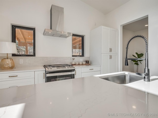 kitchen with white cabinetry, stainless steel range, wall chimney range hood, and sink