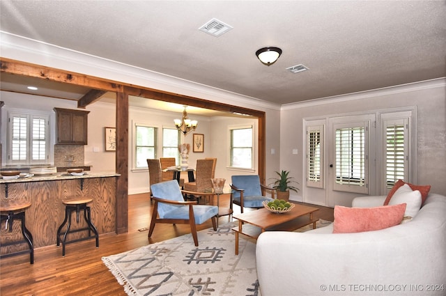 living room featuring hardwood / wood-style flooring, a notable chandelier, crown molding, and a textured ceiling