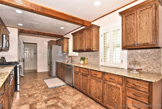 kitchen featuring decorative backsplash, light stone countertops, sink, and appliances with stainless steel finishes