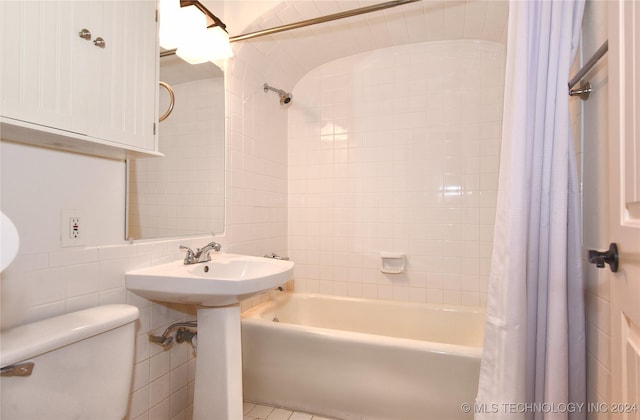 bathroom featuring tile patterned flooring, toilet, tile walls, and shower / tub combo with curtain