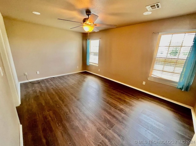 unfurnished room featuring dark hardwood / wood-style floors, a wealth of natural light, and ceiling fan