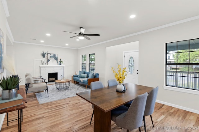 dining room with ceiling fan, light hardwood / wood-style flooring, a premium fireplace, and ornamental molding