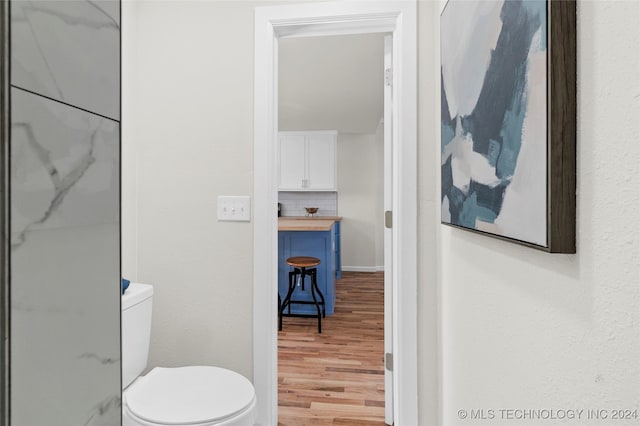 bathroom featuring decorative backsplash, toilet, and wood-type flooring