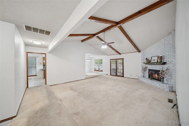 unfurnished living room with ceiling fan, light colored carpet, a textured ceiling, and a brick fireplace