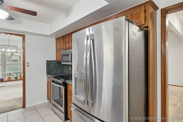 kitchen with decorative backsplash, ceiling fan, a textured ceiling, light colored carpet, and stainless steel appliances