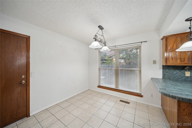 unfurnished dining area with light tile patterned flooring and a textured ceiling