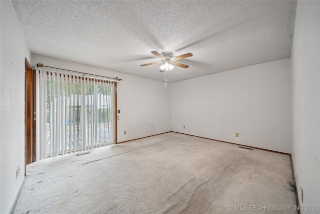 empty room with ceiling fan, light colored carpet, and a textured ceiling