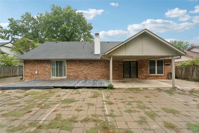 rear view of house with a wooden deck and a patio area