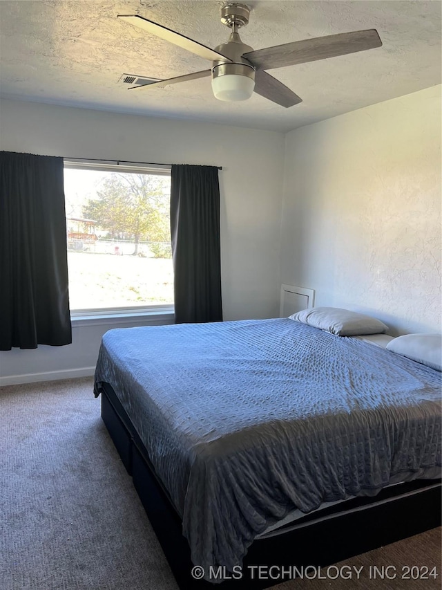 carpeted bedroom with ceiling fan and a textured ceiling