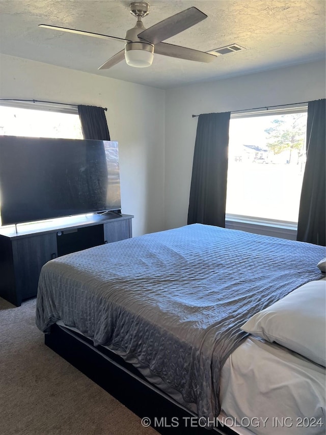 bedroom featuring ceiling fan, carpet floors, and a textured ceiling