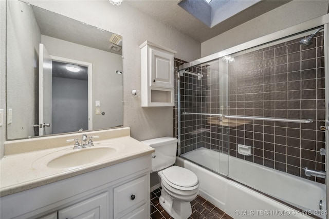 full bathroom with shower / bath combination with glass door, vanity, a skylight, and toilet