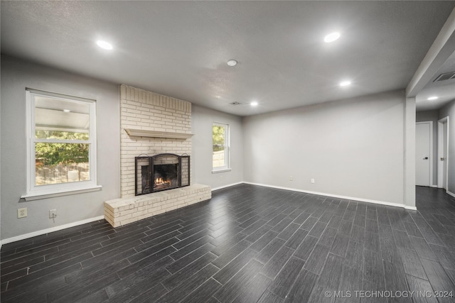 unfurnished living room featuring dark hardwood / wood-style floors and a brick fireplace