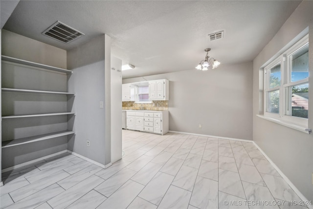 interior space featuring built in shelves, a textured ceiling, an inviting chandelier, and sink