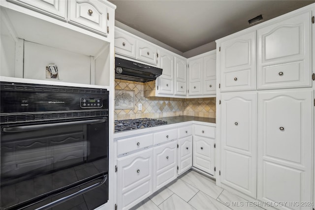 kitchen with stainless steel gas stovetop, black oven, white cabinets, and tasteful backsplash