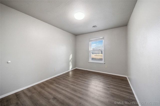 empty room featuring a textured ceiling and dark hardwood / wood-style floors