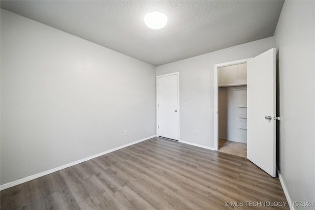 unfurnished bedroom featuring wood-type flooring, a textured ceiling, and a closet