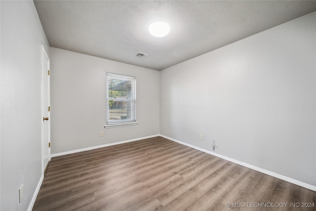 unfurnished room featuring hardwood / wood-style floors and a textured ceiling