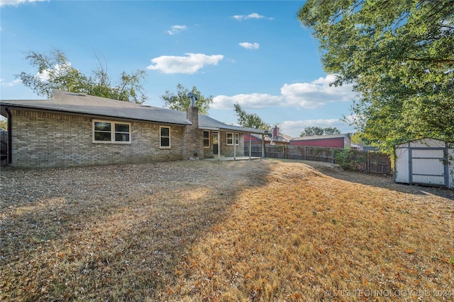 rear view of house featuring a storage shed and a lawn